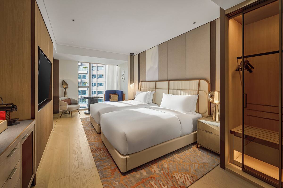 Una habitación de hotel moderna con una cama grande, un escritorio, un televisor y vistas a la ciudad.
