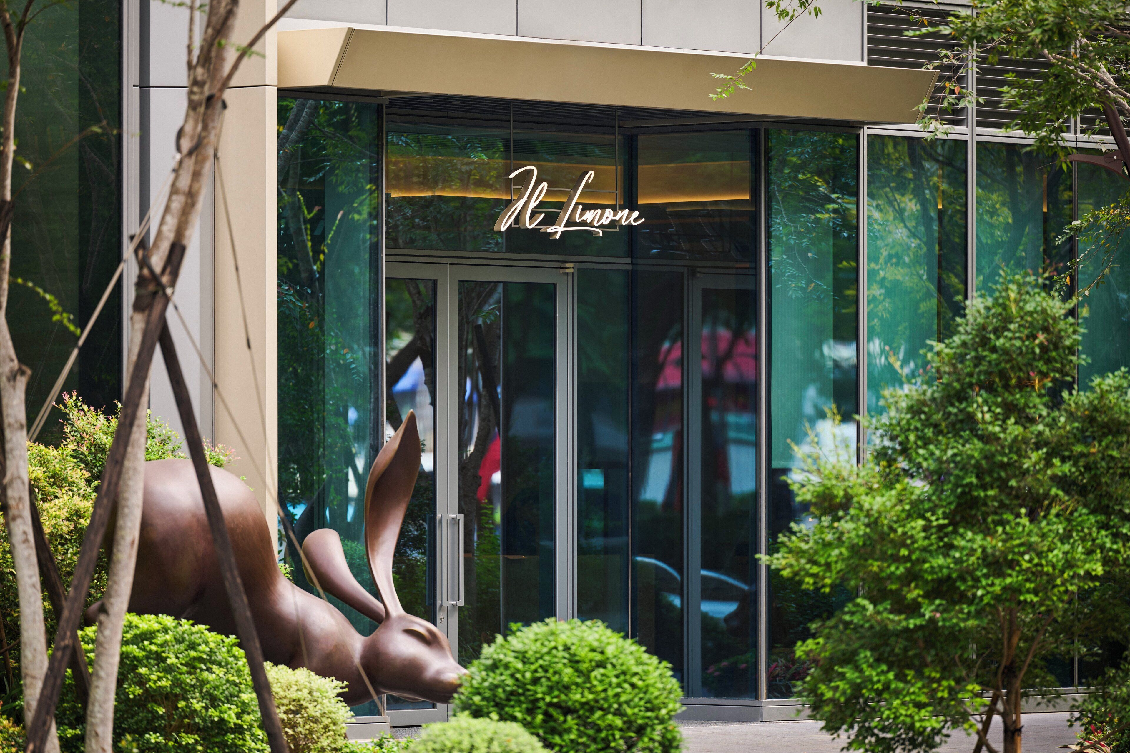A building entrance with a glass facade and a bronze sculpture of a deer.