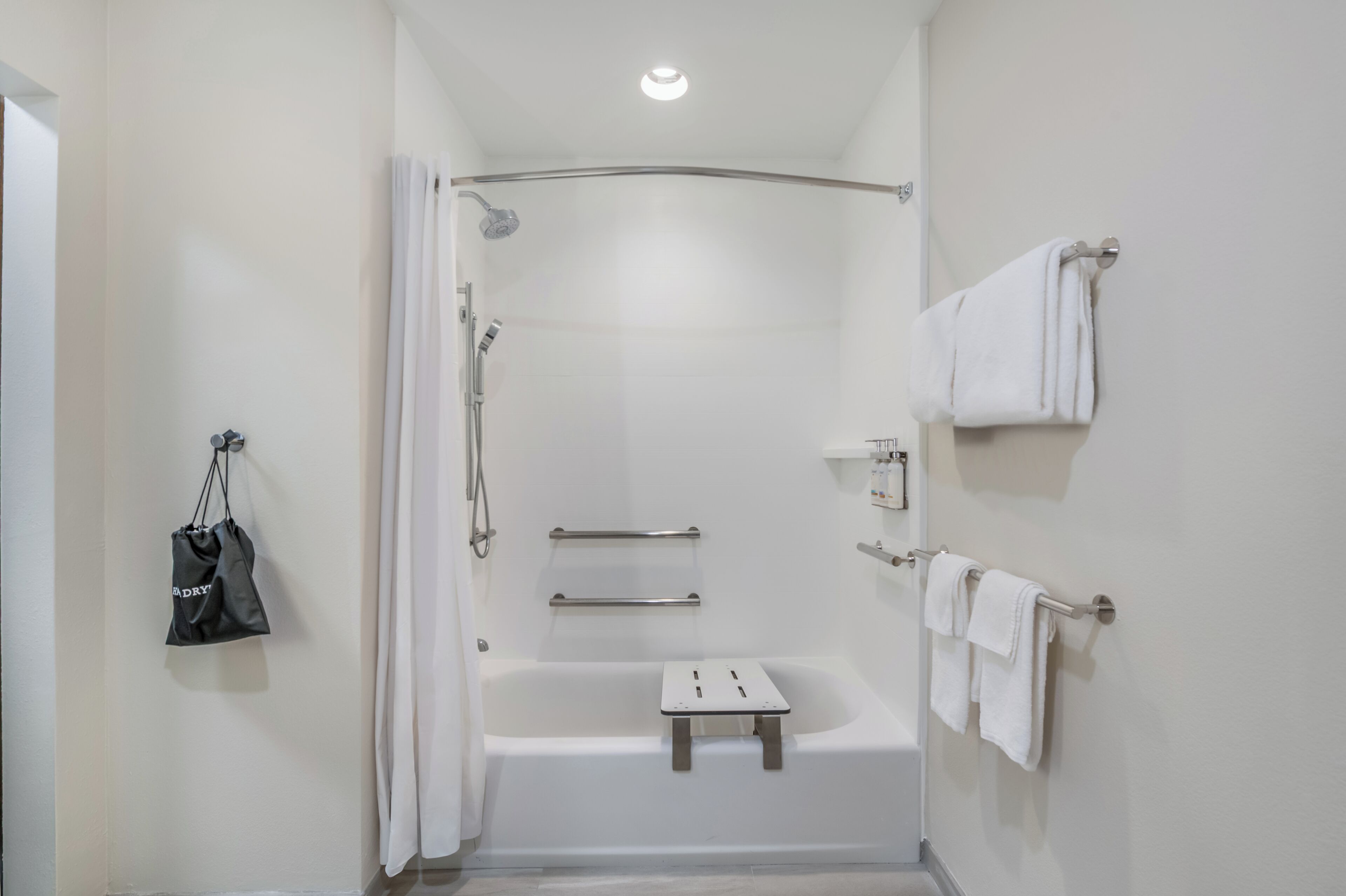 Un baño moderno con ducha, bañera, toallero y un estante pequeño.
