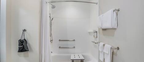 Un baño moderno con ducha, bañera, toallero y un estante pequeño.