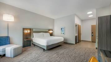 Una camera d'albergo con un letto, comodini, una lampada, una sedia e un armadio.