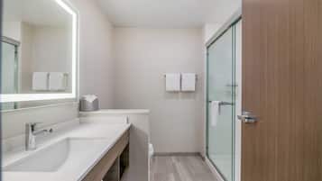 A modern bathroom with a large mirror, a sink, a toilet, and a glass shower enclosure.