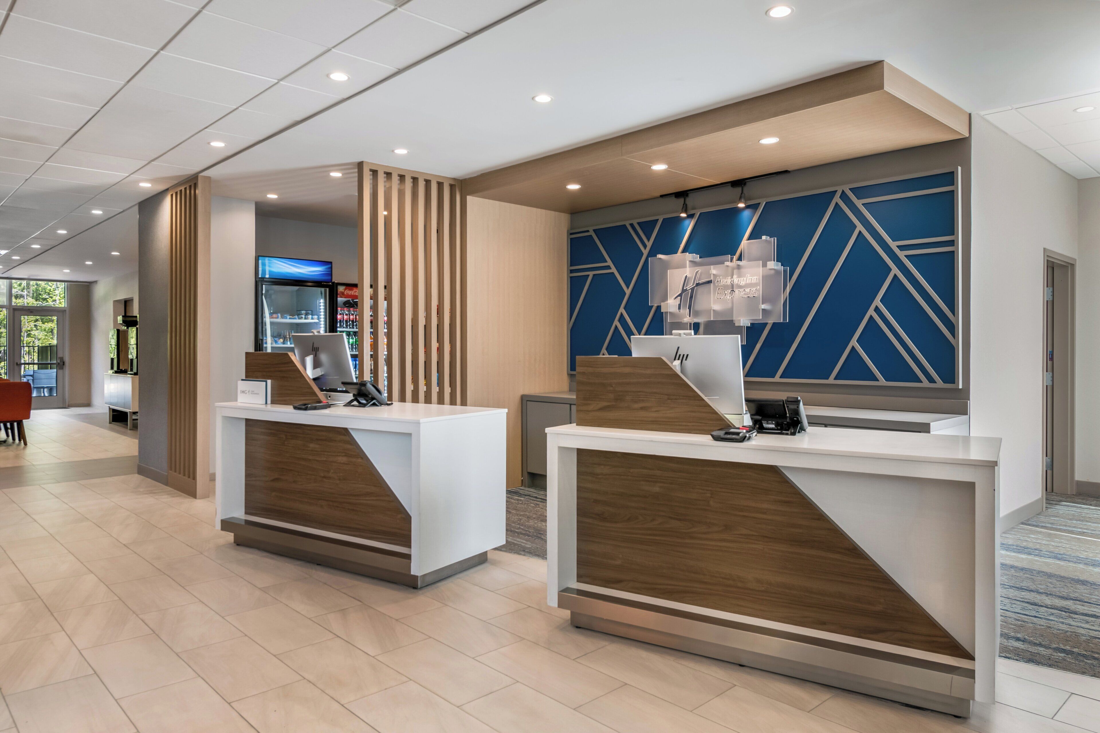A reception desk with a modern design, a coffee machine, and a wall with geometric patterns.