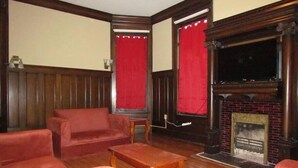 A room with a fireplace, red curtains, a sofa, and a wooden coffee table. - Peabody Backhouse 5 (Memphis)