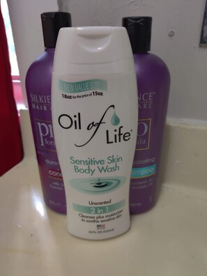 Una bottiglia di Oil of Life Sensitive Skin Body Wash su un ripiano del bagno.