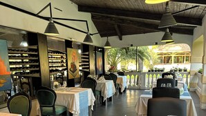 Ein Restaurant mit gedeckten Tischen, das ein modernes Interieur mit Holzbalken und Pendelleuchten zeigt.
