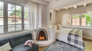 A cozy room with a fireplace, a bed, and a sofa. - Mid-Century Modern Taos Home w/ Hot Tub & Fire Pit (Taos)