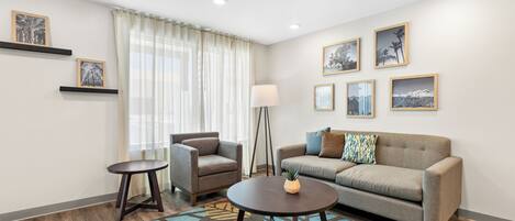 Una sala de estar moderna con sofá, sillón, mesa de centro y una lámpara de pie.