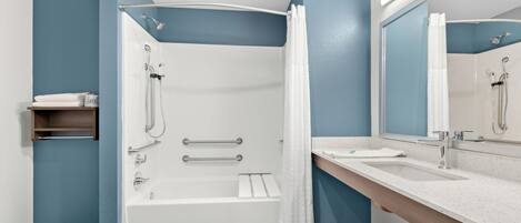 A modern bathroom with a bathtub, shower, and a large mirror.
