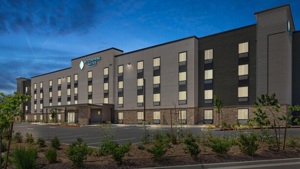 A modern hotel building with a flat roof, multiple windows, and a parking lot. - Woodspring Suites Ceres - Modesto (Ceres)