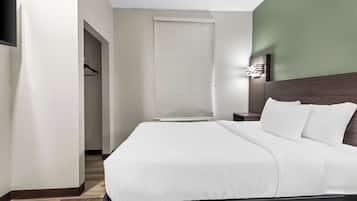 A hotel room with a bed, a nightstand, a wall-mounted light, and a closet with a hanging rack.
