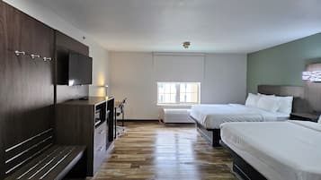 Una habitación de hotel moderna con un banco de madera, dos camas, un televisor de pantalla plana y un ventanal grande.