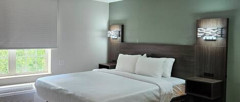 A modern bedroom with a large bed, built-in nightstands, and a wall-mounted light fixture.