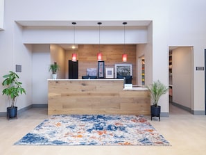 Un mostrador de recepción con detalles de madera, dos lámparas colgantes y una alfombra colorida.