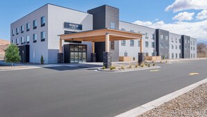 Ett modernt hotell med en inglasad entré, flera våningar och en skylt med texten ”VOCO BY INGO”.