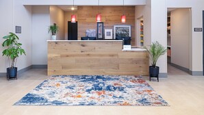 En receptionsdisk med träinredning, en blå och orange mönstrad matta och tre hänglampor.