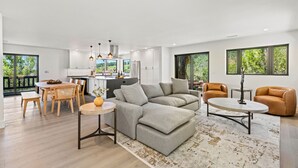A modern living room with a grey sectional sofa, a round coffee table, and a dining area with wooden chairs.