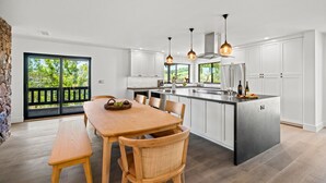 A modern kitchen with a central island, white cabinetry, and pendant lighting.