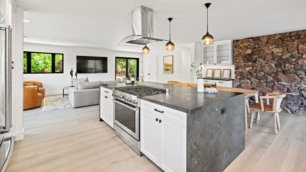 A modern kitchen with a central island, built-in oven, and pendant lighting.
