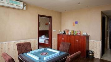 A hotel room with a dining table, chairs, a minibar, and a door leading to a bathroom.