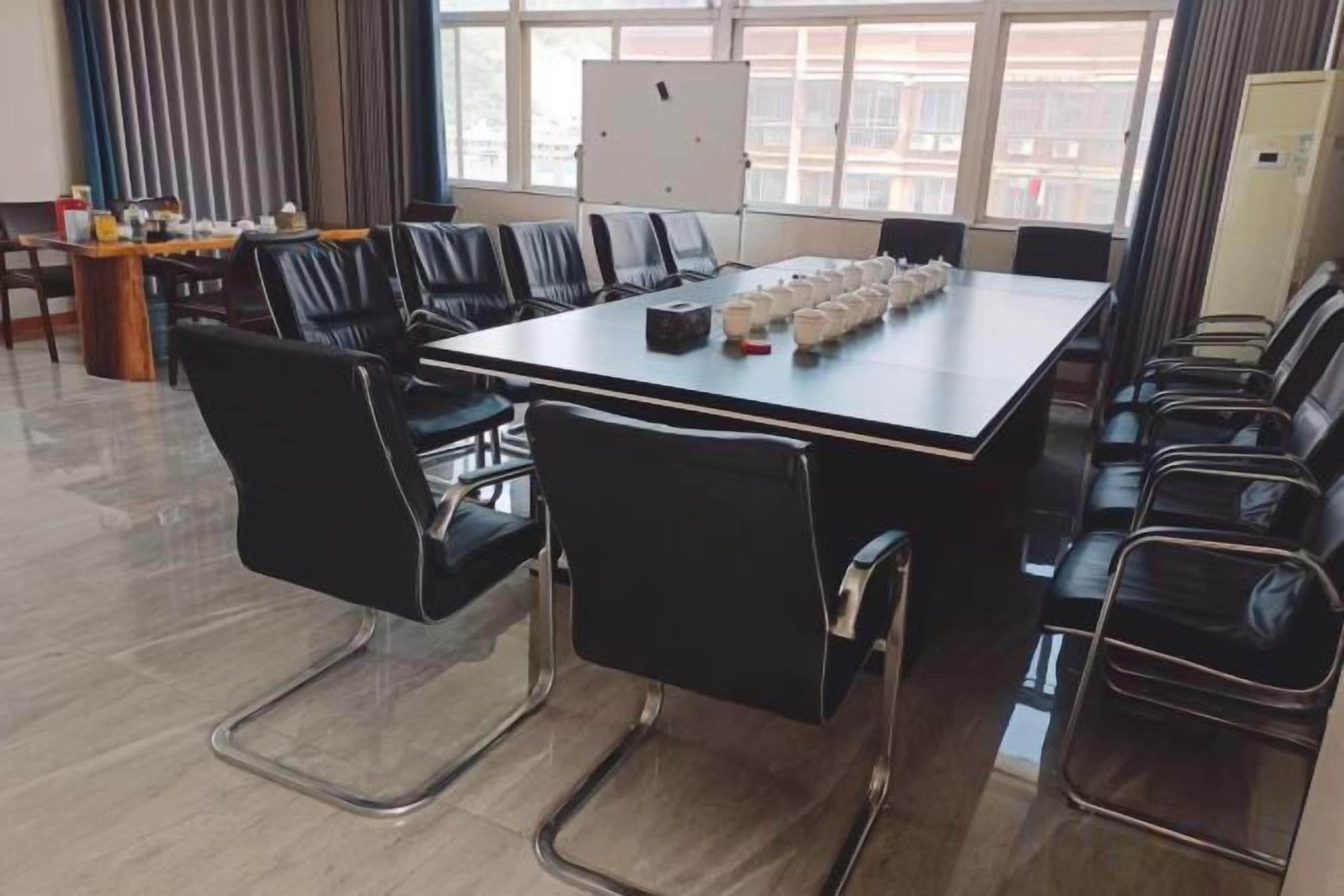 A conference room with a long table, black chairs, and a whiteboard.
