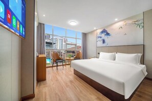 Quarto de hotel com uma cama grande, uma mesa e uma cadeira.