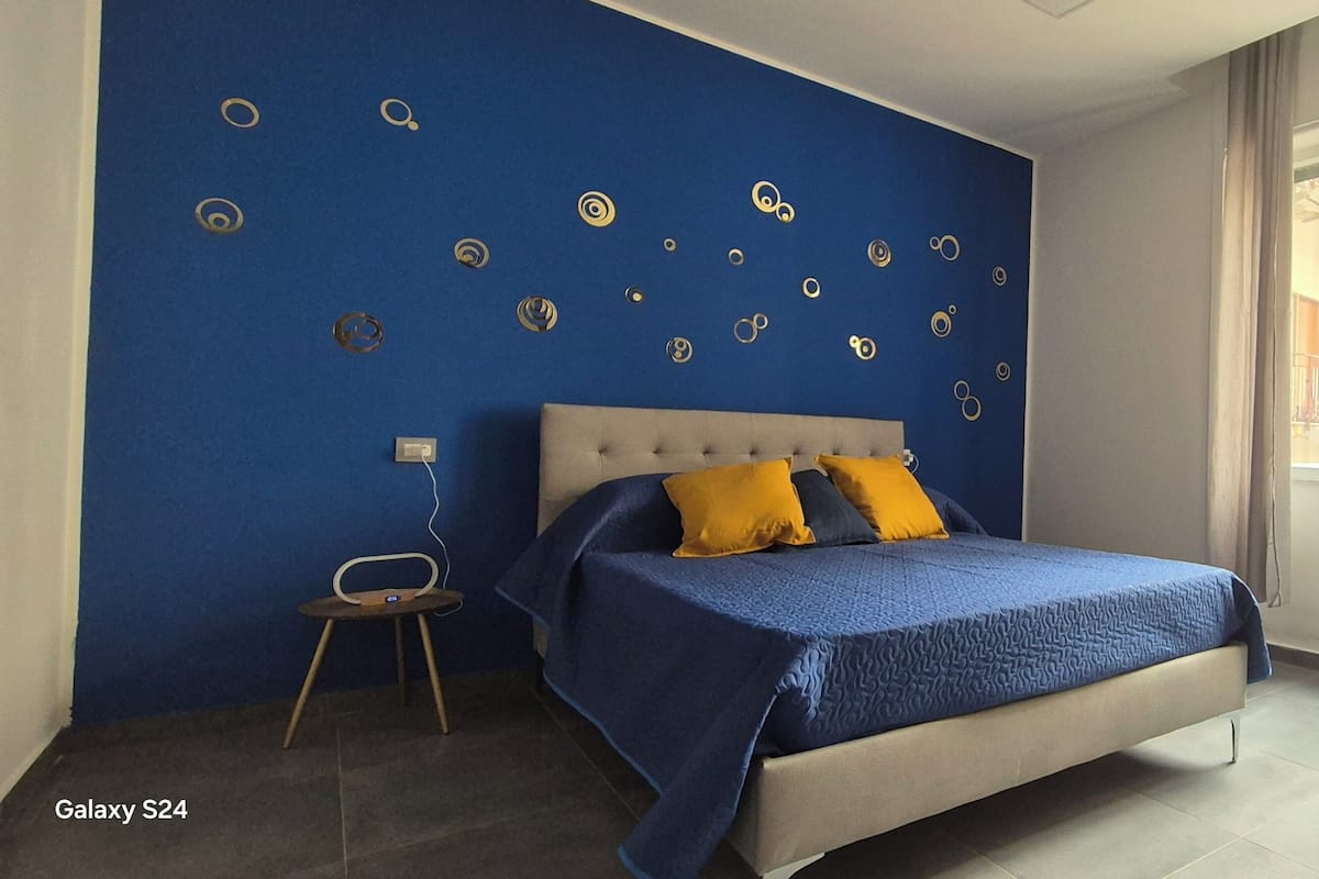 A bedroom with a bed, a chair, a window, and wall decorations.