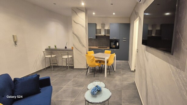 A compact living space with a dining area, a sofa, and a small table with flowers. - B & B Malì (Salerno)