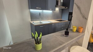 A modern kitchen with grey cabinets, a stainless steel sink, and a small potted plant. - B & B Malì (Salerno)
