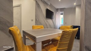 A modern dining area with a marble wall, a flat-screen TV, and yellow upholstered chairs. - B & B Malì (Salerno)