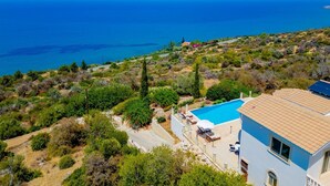Una villa de estilo mediterráneo con piscina, rodeada de exuberante vegetación y vistas a un paisaje costero.