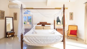 Una cama con dosel, una mesita de noche de madera, una silla y un espejo grande.
