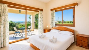 Une chambre à coucher comprenant un lit, une table de chevet, une tête de lit en bois, une fenêtre et un balcon avec une table et des chaises.