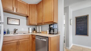 Una cucina moderna con mobili in legno, elettrodomestici in acciaio inossidabile e una lavagna che accoglie gli ospiti in un centro benessere.