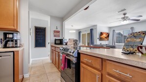 Una cucina moderna con mobili impiallacciati in legno, forno a incasso, microonde e macchina per il caffè.