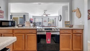 Cucina con mobili in legno, un forno a microonde, un fornello e un asciugamano rosso appeso alla porta del forno.