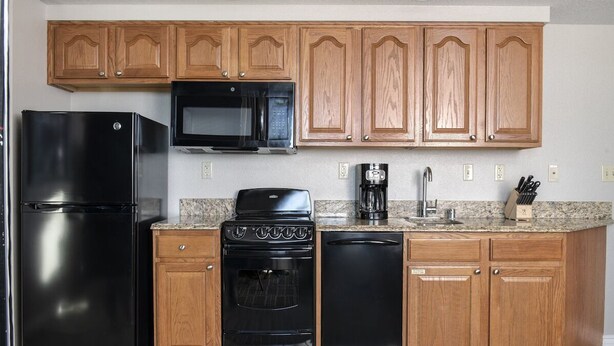 A kitchen with wooden cabinets, a black refrigerator, a microwave, an oven, and a dishwasher. - Grand Desert 1 Bedroom Suite, Las Vegas! (Las Vegas)