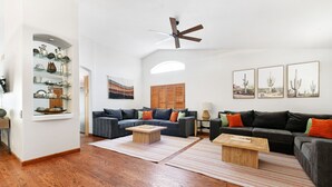 Un amplio salón con suelo de madera, dos sofás, una mesa de centro y un ventilador de techo.