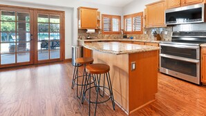 Una cocina amplia con armarios de madera, encimera de granito y electrodomésticos de acero inoxidable.