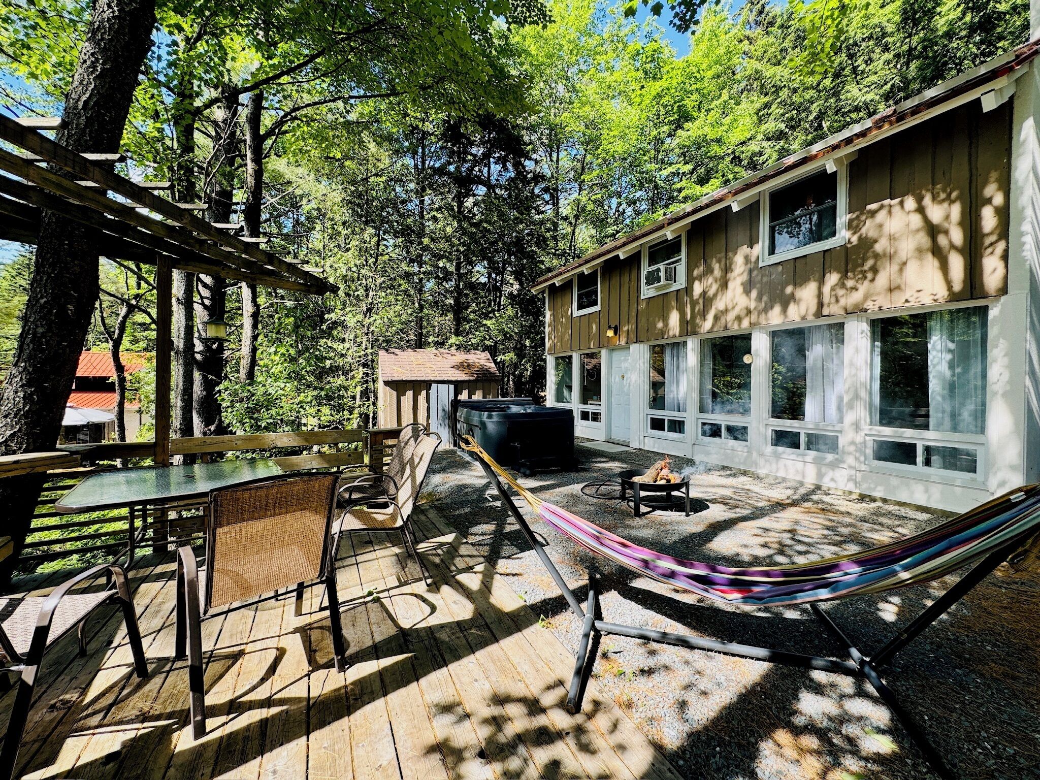 A wooden deck with outdoor furniture, a hammock, and a barbecue grill.