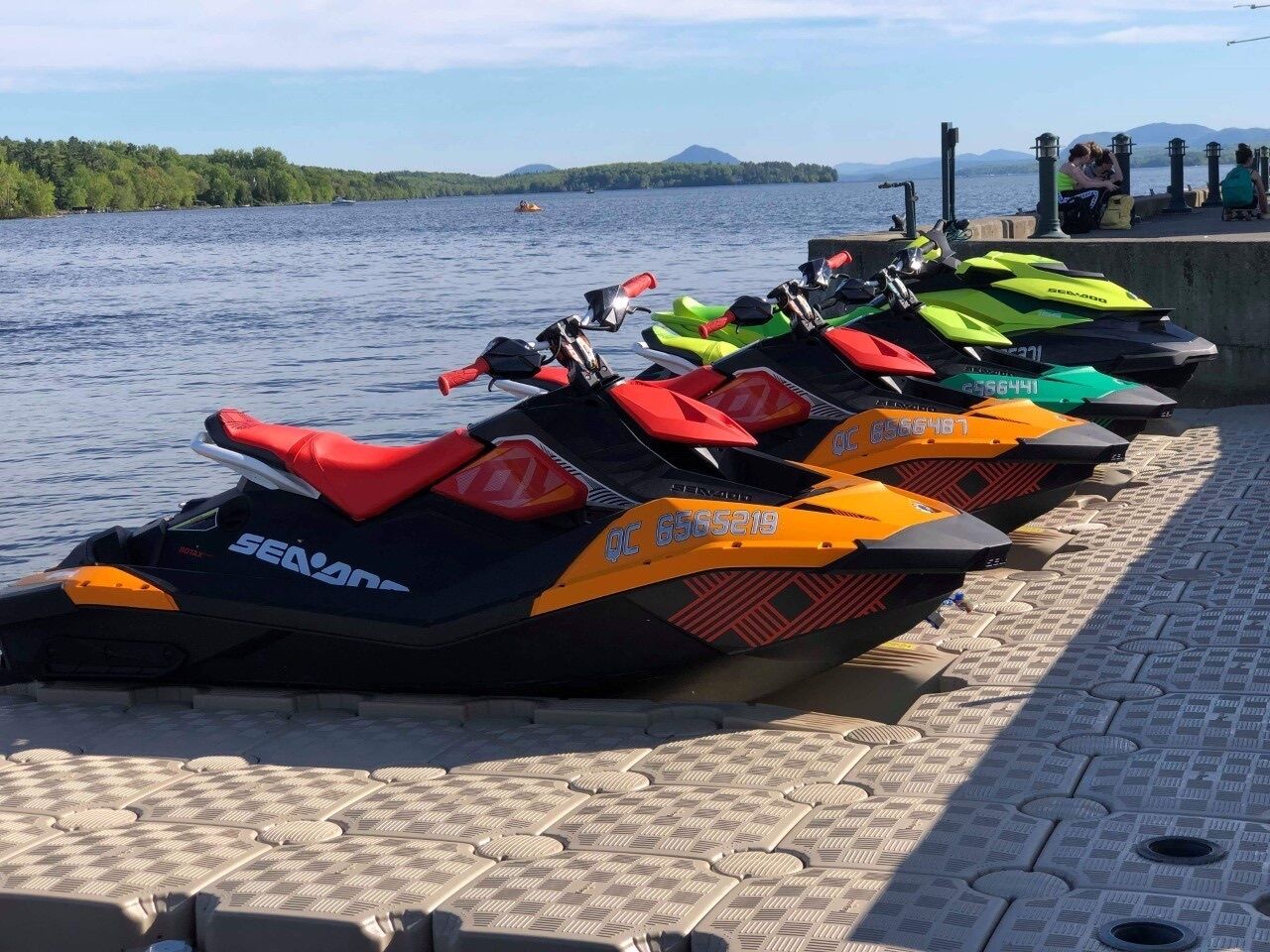 A row of colorful jet skis lined up on a dock by a lake.