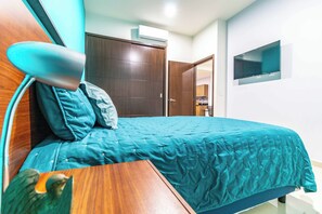 A bedroom with a bed, a wooden nightstand, a desk, a TV mounted on the wall, and a wardrobe. - New Centric apt. with pool & jacuzzi (Mazatlán)