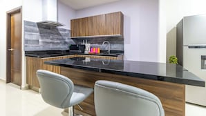 A modern kitchen with a central island, wooden cabinets, and a stainless steel refrigerator. - New Centric apt. with pool & jacuzzi (Mazatlán)