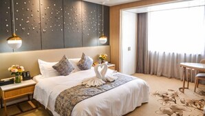 Une chambre d’hôtel avec un grand lit, une table de chevet, un bureau et une vue sur l’extérieur.