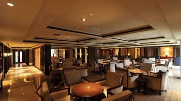 A spacious hotel lobby with multiple seating areas, a reception desk, and a well-lit environment.