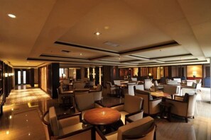 Eine großzügige Hotelhalle mit mehreren Sitzbereichen, einem Empfangsbereich und heller Atmosphäre.