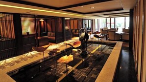 Un hall d’hôtel moderne doté d’un élément décoratif central en eau, d’espaces aménagés pour s’asseoir et de grandes fenêtres laissant entrer la lumière naturelle.