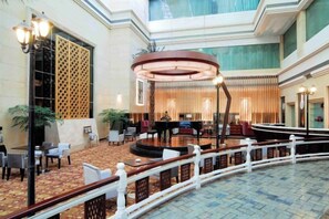 A hotel lobby with a central seating area, a reception desk, and a staircase. - Sunlit Hotel (Jianyang)