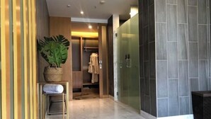 Une salle de bain moderne avec un sol en marbre, une plante en pot, un porte-serviettes et une cabine de douche en verre.