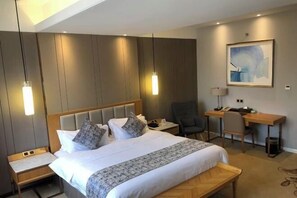 A modern hotel room with a large bed, bedside tables, a desk, and a chair. - Sunlit Hotel (Jianyang)